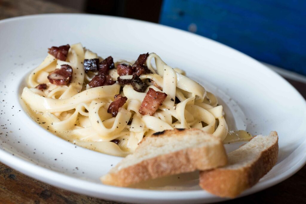 Pasta Carbonara Dish With Bread on White Ceramic Plate.