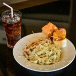 Close-Up Shot of a Plate of Pasta Carbonara beside a Glass of Soft Drink.