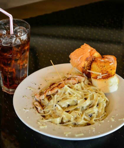 Close-Up Shot of a Plate of Pasta Carbonara beside a Glass of Soft Drink.