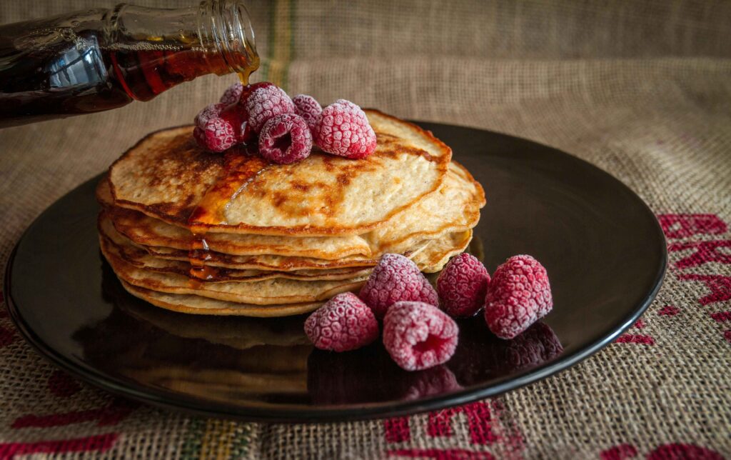 The pancake is served on a black plate and garnished with berries.