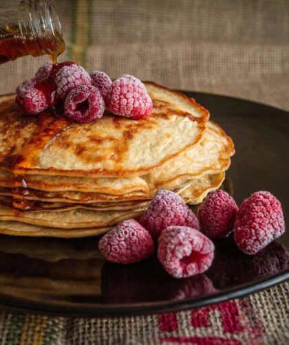 The pancake is served on a black plate and garnished with berries.