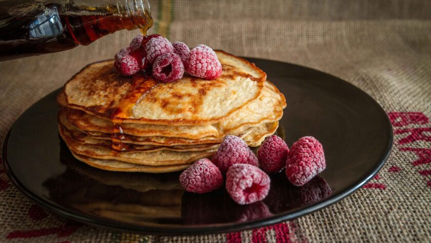 The pancake is served on a black plate and garnished with berries.