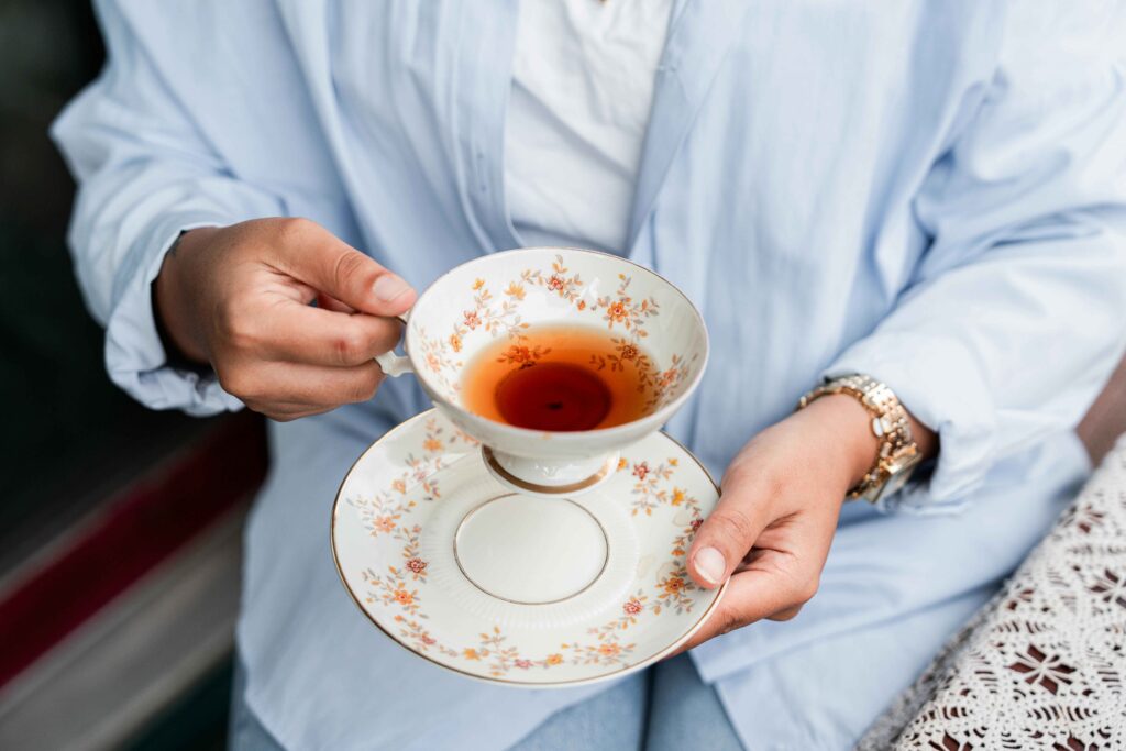 A person is holding a cup filled with Lemon and Ginger Tea