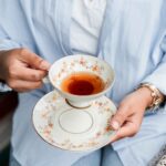 A person is holding a cup filled with Lemon and Ginger Tea