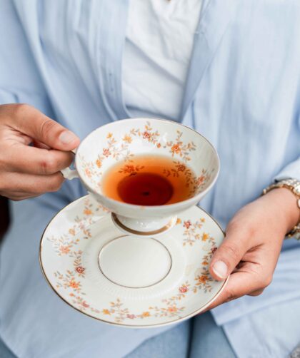 A person is holding a cup filled with Lemon and Ginger Tea