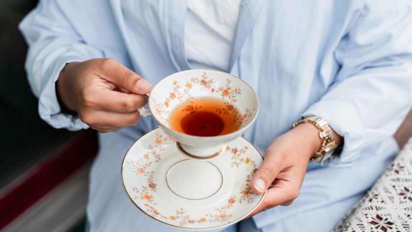 A person is holding a cup filled with Lemon and Ginger Tea